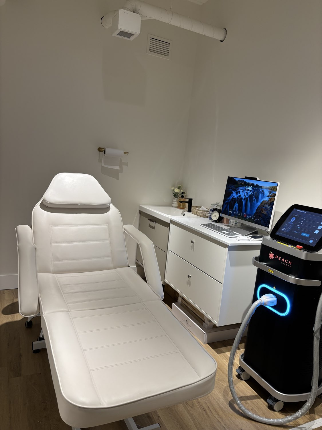 Peach Lasers Calgary treatment room with the branded 4-wavelength Diode Laser machine, white treatment bed, and professional clinical setup